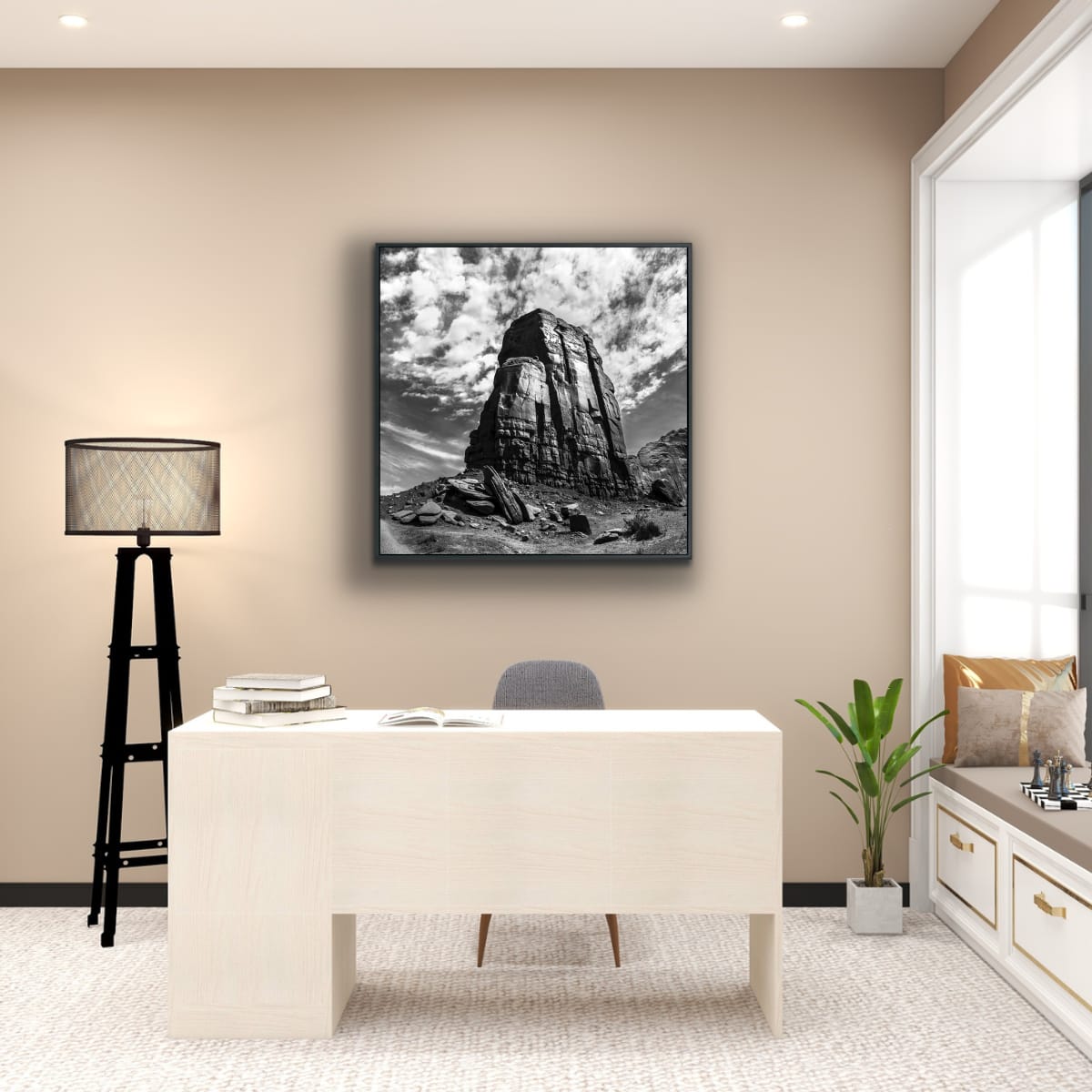 Modern home office interior with a desk, lamp, and framed picture of a Monument Valley rock formation against cloudy curved dramatic sky in black and white.