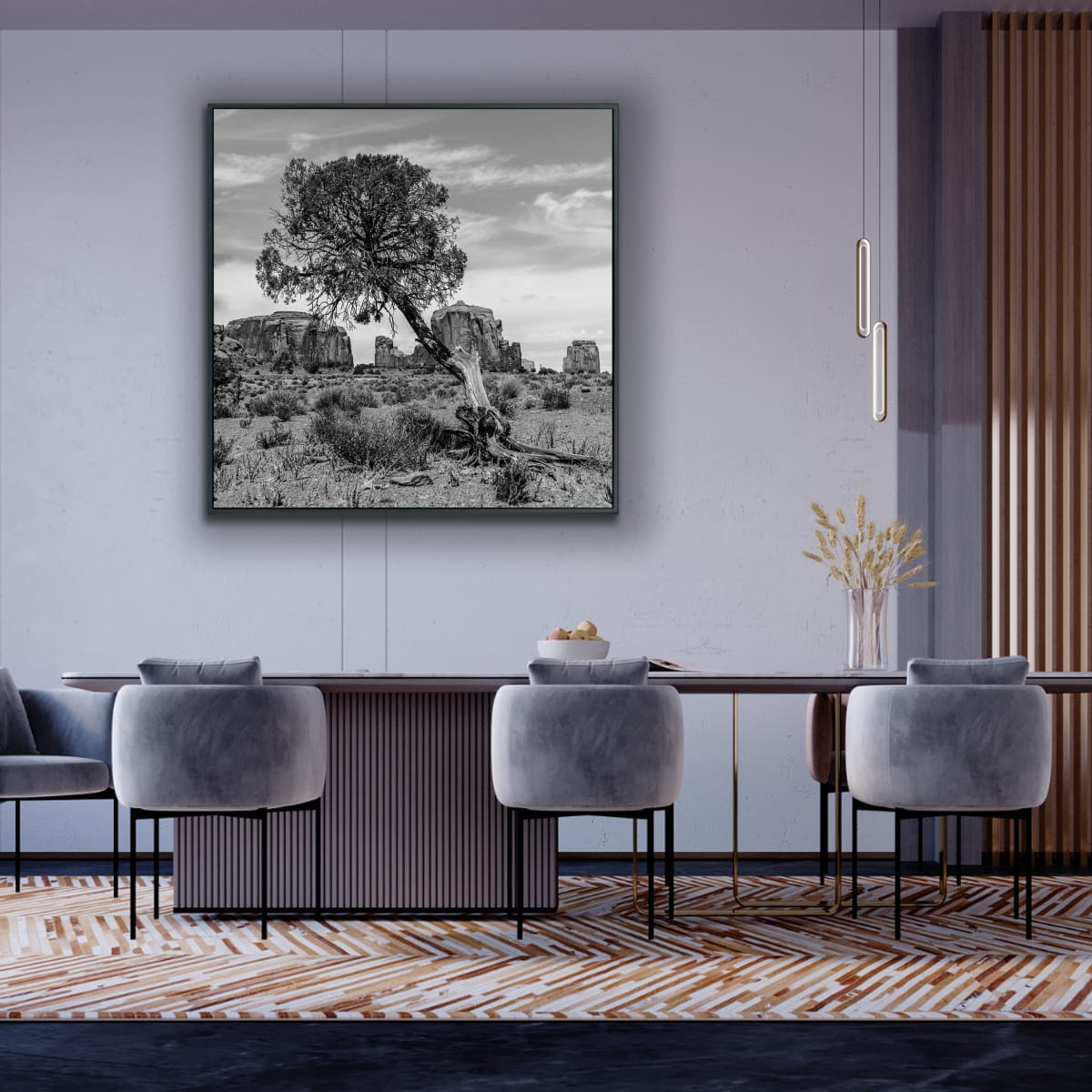 Modern dining room with gray chairs, a wooden table, and a large framed landscape painting on the wall featuring a black and white photograph of a lone slanted tree Monument Valley rock formations in background.