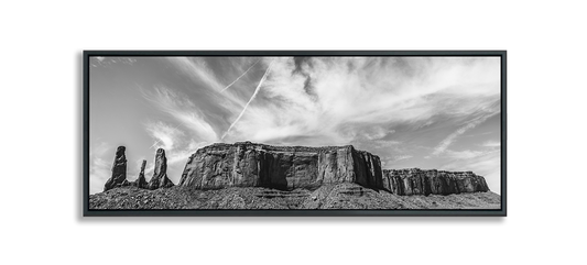 Monument Valley Three Sisters next to Desert Butte against dramatic clouds in sky