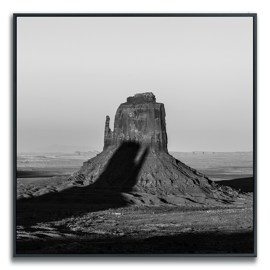 Black and white photograph of an iconic Monument Valley butte being shadowed by another iconic butte.