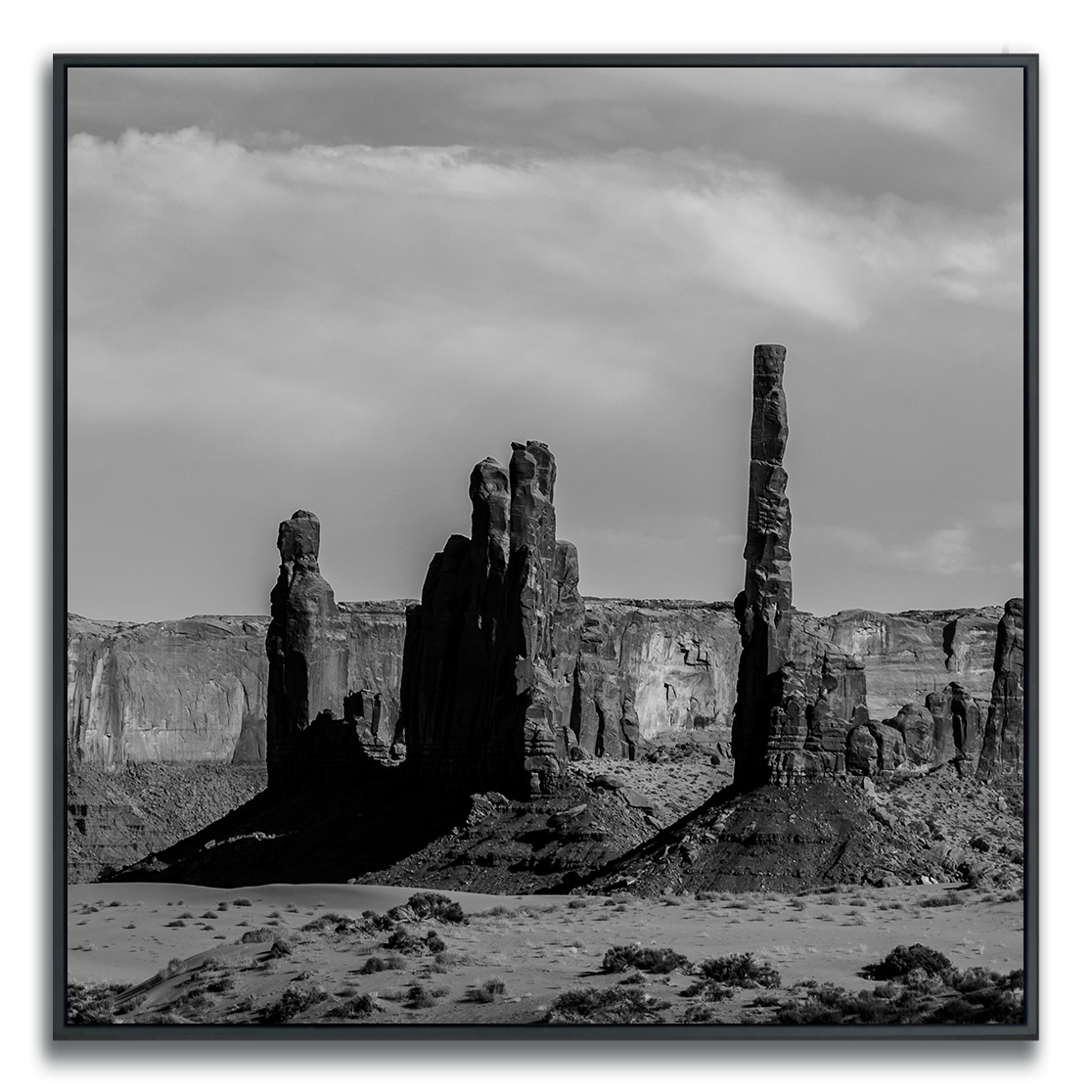 Framed artwork of a black and white square print of Monument Valley desert butte spires.