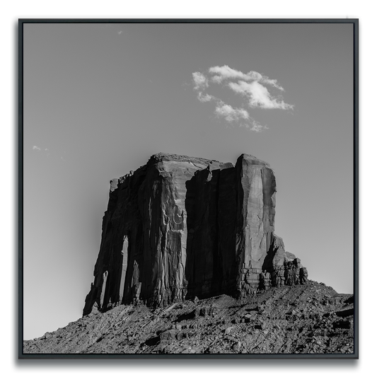 Framed black and white square metal print of a Monument Valley solitary butte with a single sparse cloud formation in the sky above it.