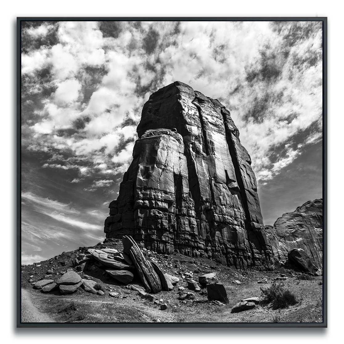 Monument Valley rock formation against cloudy curved dramatic sky in black and white.