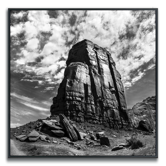 Monument Valley rock formation against cloudy curved dramatic sky in black and white.