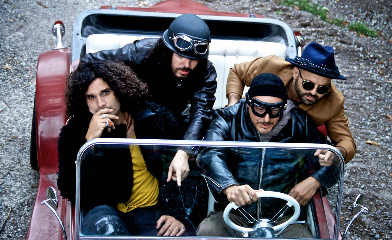 Musical group portrait Celebration Army driving vintage red convertible members leaning towards windshield