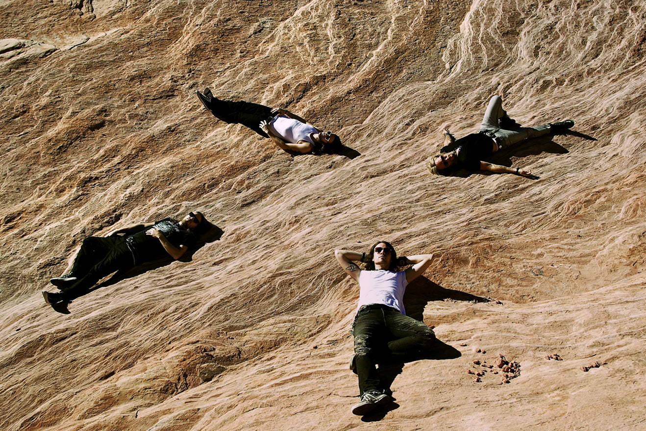 Band photo One Bad Son members lying  on ground Valley Of Fire heads pointed toward center of image