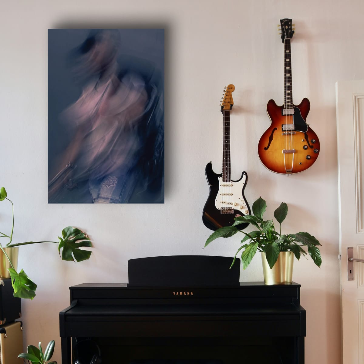 Two guitars on a wall above a piano with a painting and plants in the room.