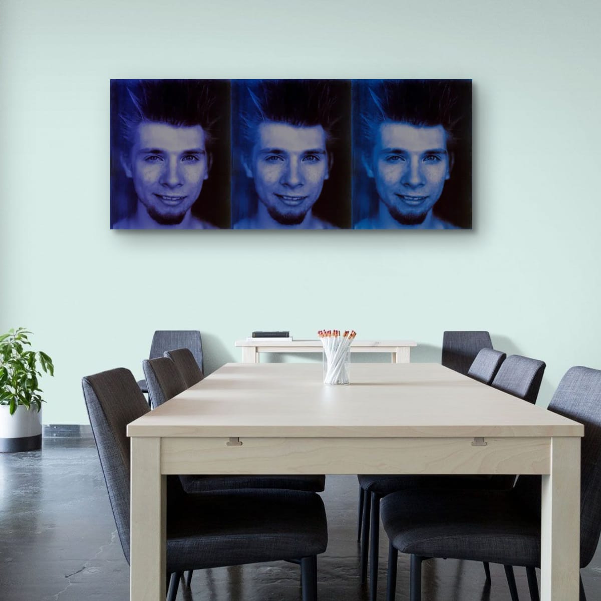 Dining room with a large table and chairs, featuring a wall art of a person's face.