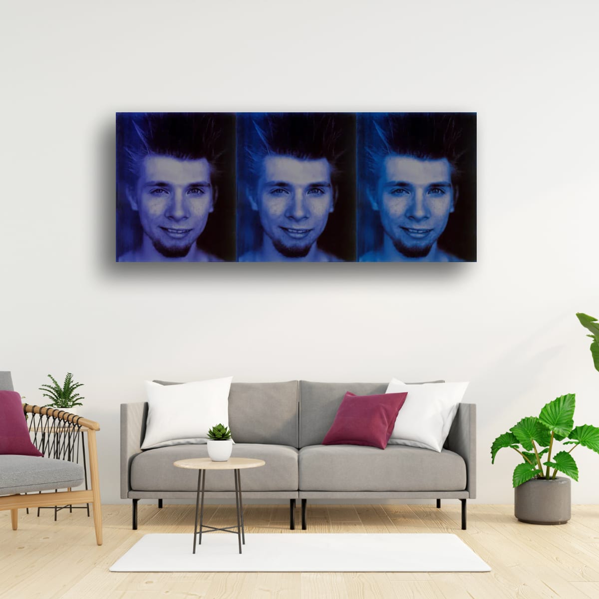 Living room with a gray sofa, small table, and decorative pillows, featuring a large wall art of a person's face.