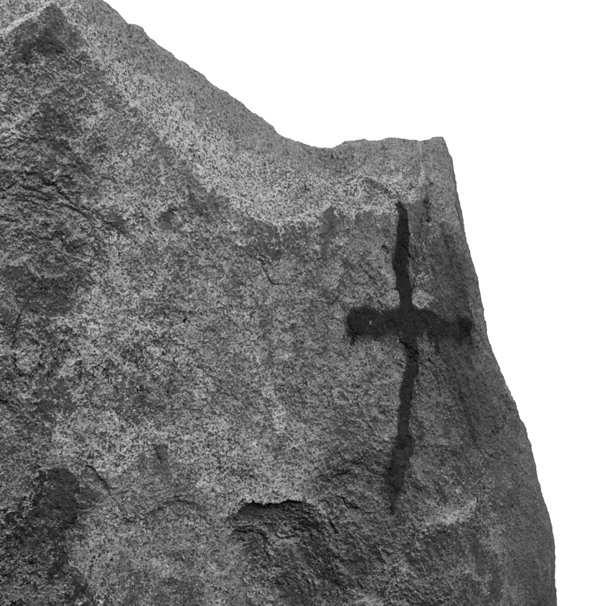 Close-up of a textured stone surface with a cross engraving.