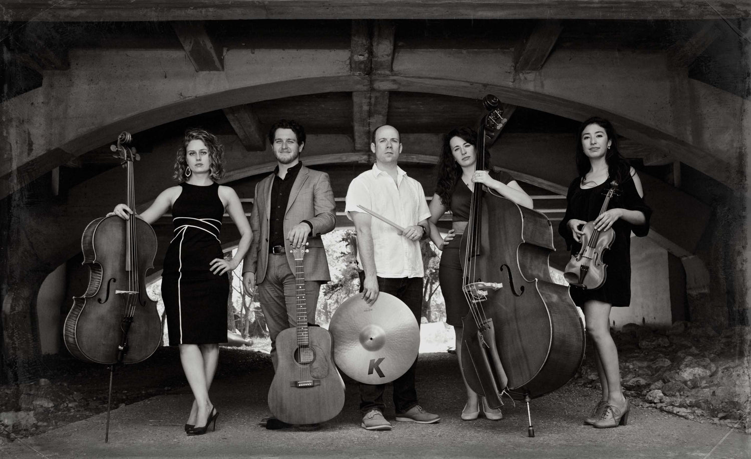 Classical music group black and white American Dreamer holding instruments under bridge