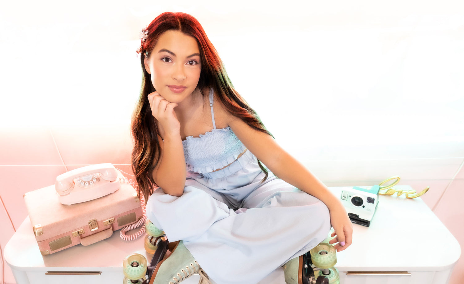 Female musician portrait Reese Warren  sitting cross legged wearing roller skates beside old photo and camera