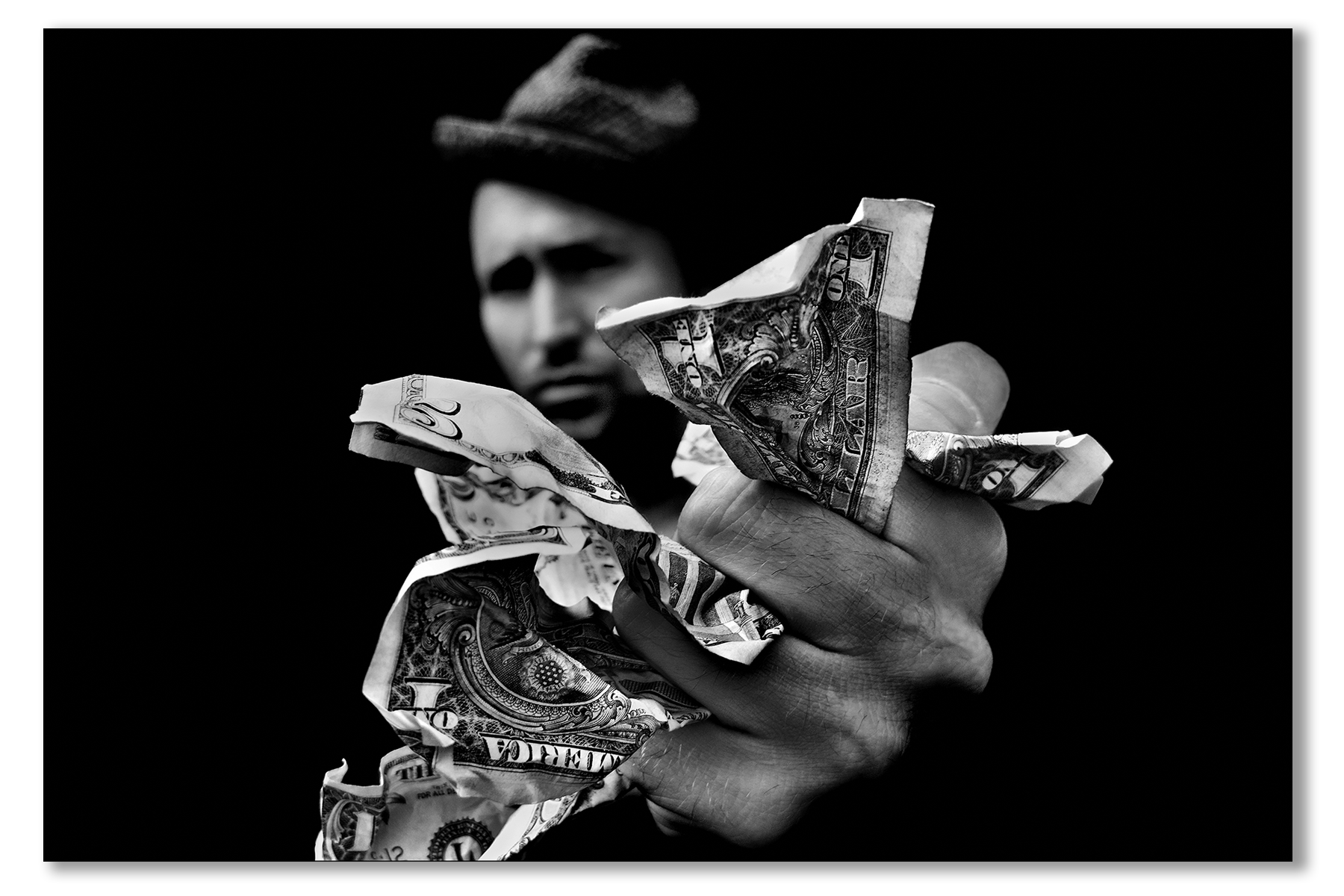 Person holding crumpled dollar bills against a black background