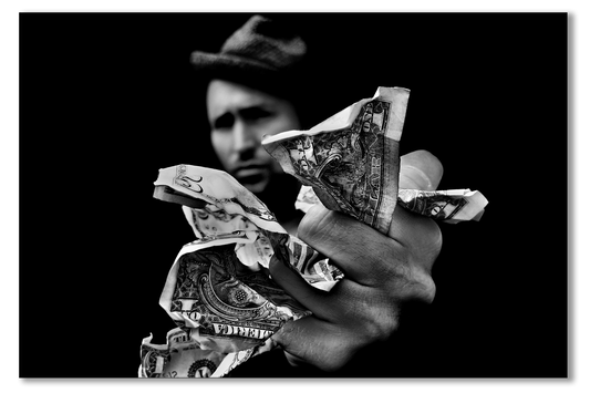 Person holding crumpled dollar bills against a black background