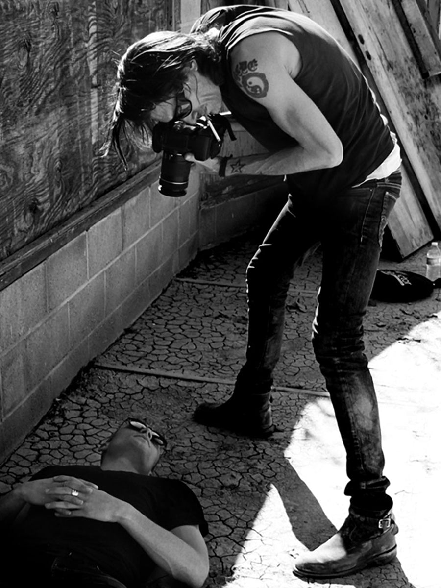 Mark Maryanovich behind the scenes photo standing over subject pointing camera down in black and white