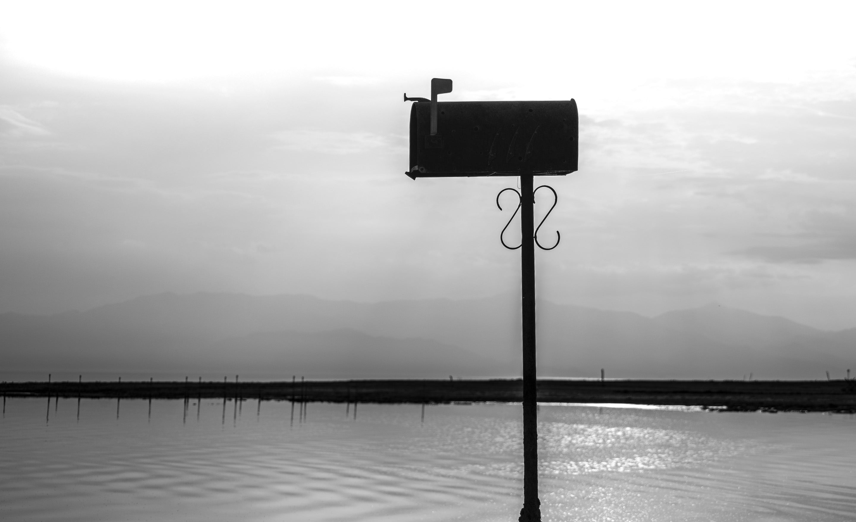 Mailbox with flag up standing in water Salton Sea black and white