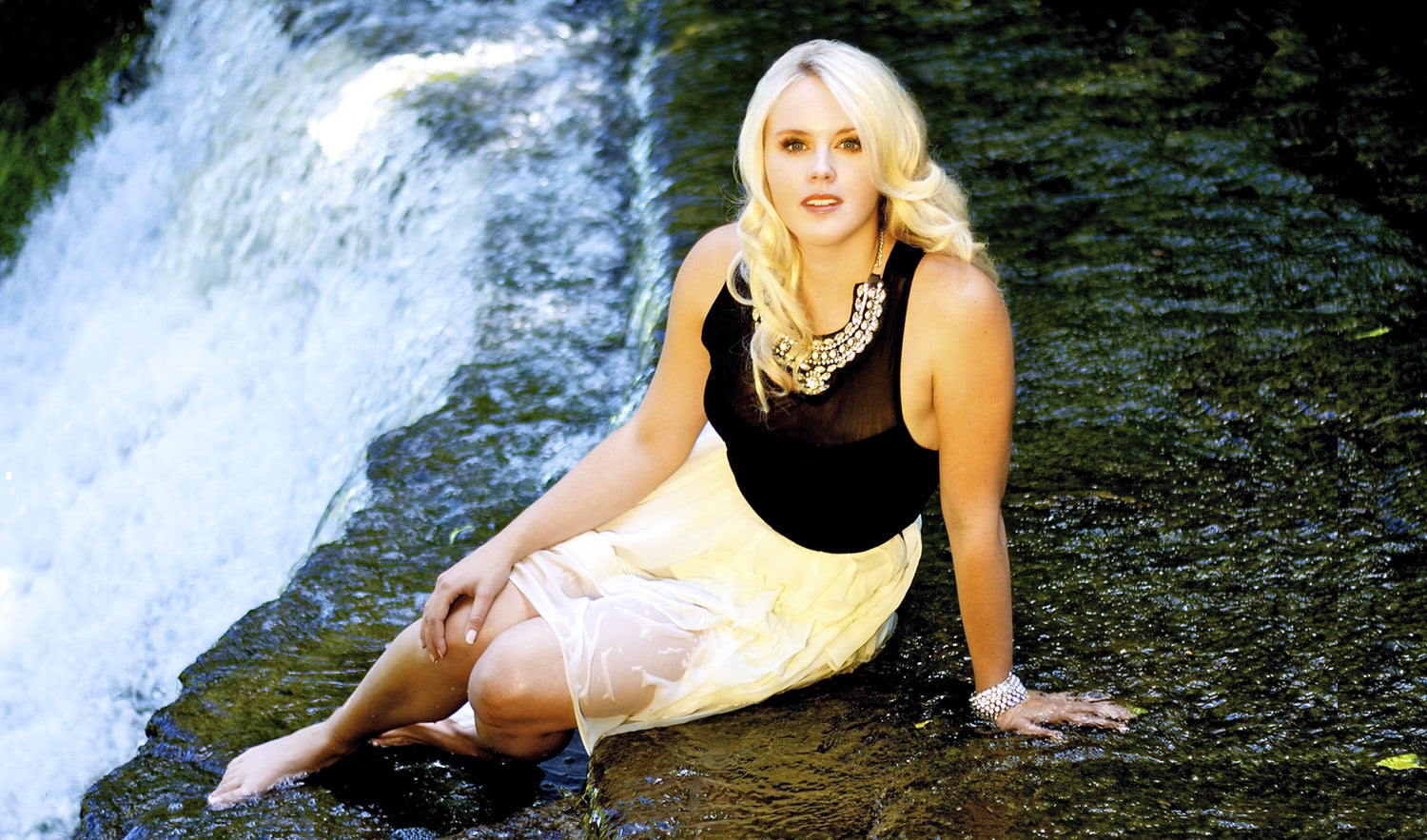 Female musician portrait Krista Earle sitting at edge of waterfall