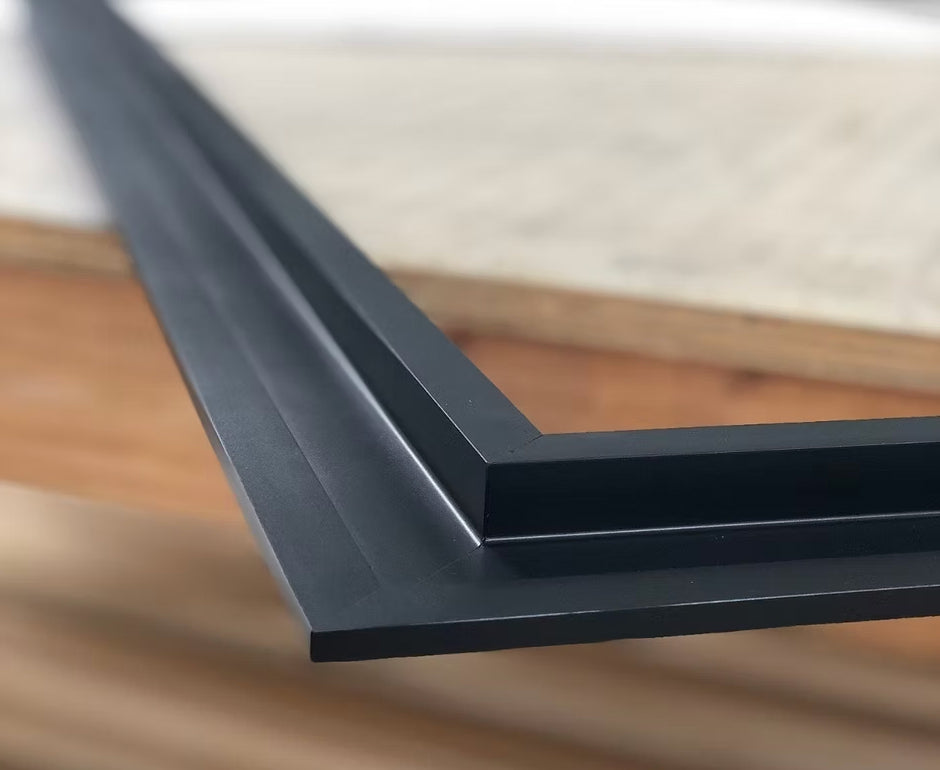 Close-up of a black picture frame corner on a wooden surface