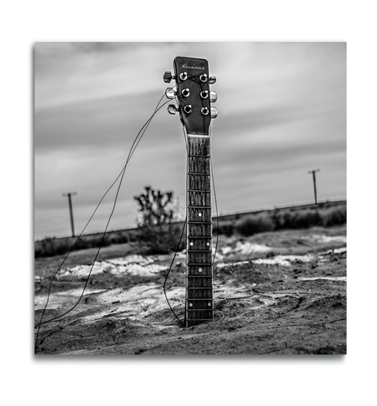 Fine Art black and white metal square print guitar neck protruding from body buried in desert sand