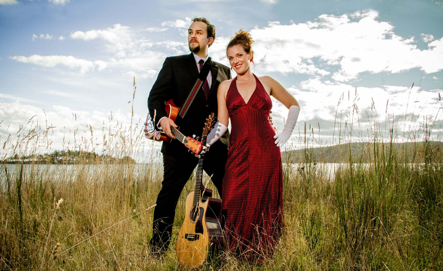 Music Duo Portrait Mad For Joy standing in grass field in suit and evening gown with gloves with instruments