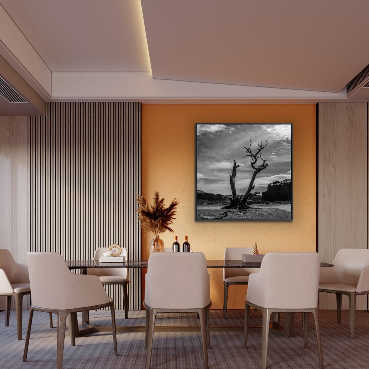 Modern dining room with long table and chairs featuring decorative wall art of of a lone, dead tree branched in two cradled by rock formations against a cloudy sky in Monument Valley photographed in black and white.