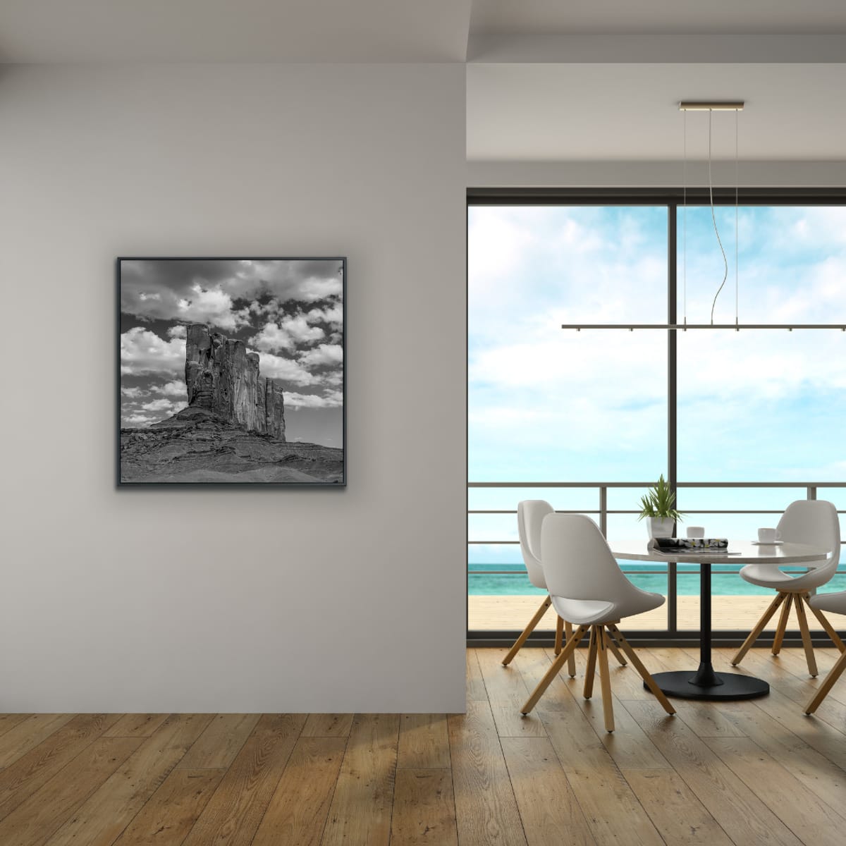 Modern interior with a framed black and white Monument Valley photograph on the wall, a dining table with chairs, and a large window ocean view.