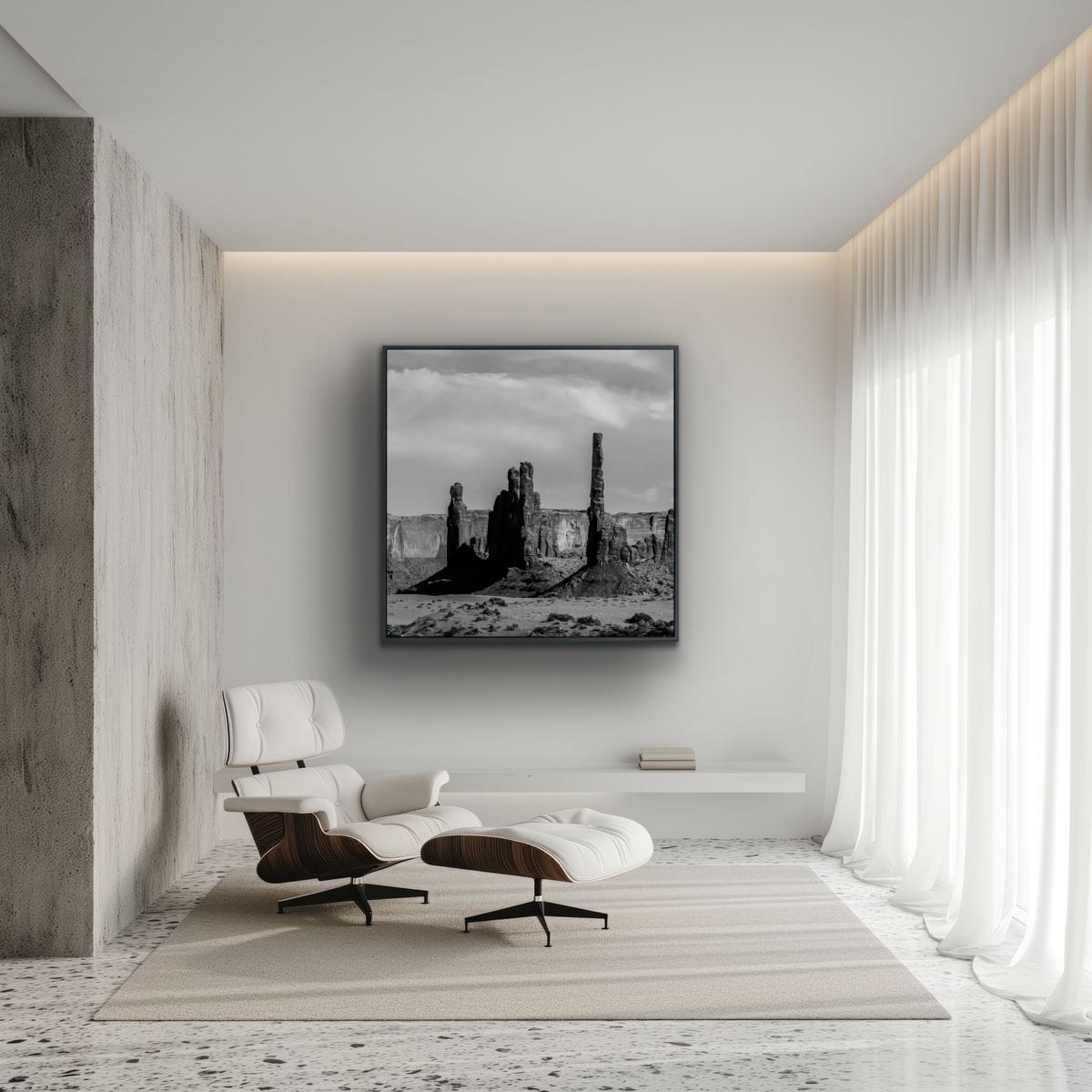Modern interior with a white lounge chair in a room lit with sun through flowing white drapes, and framed artwork of a black and white square print of Monument Valley desert butte spires.
