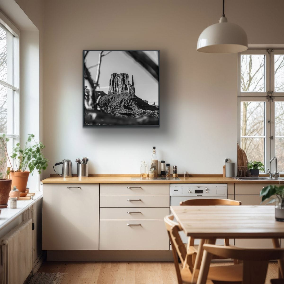 Modern kitchen with a black and white landscape print on the wall featuring a Monument Valley iconic butte, out of focus branches in foreground.