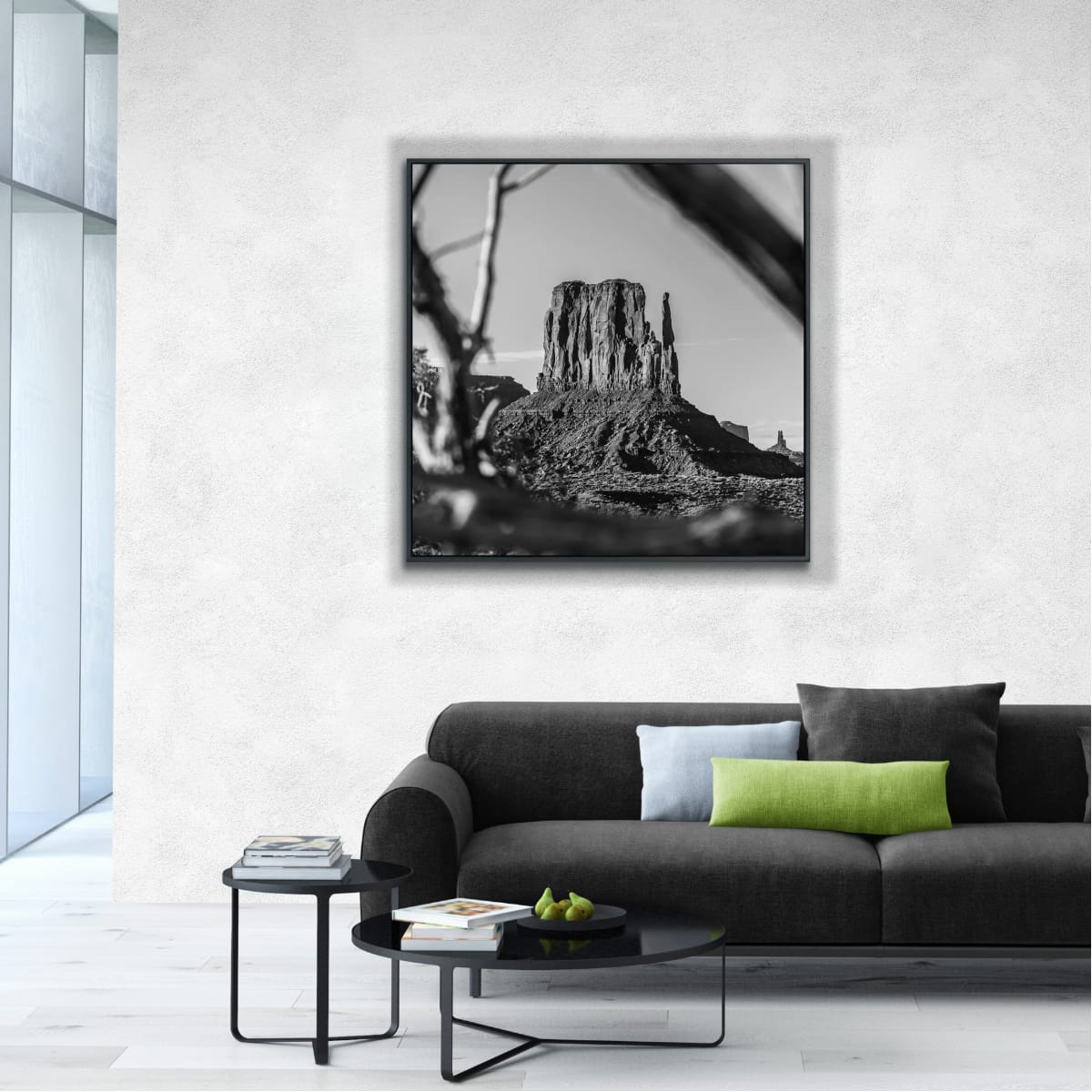 Framed black and white artwork of Monument Valley iconic butte photograph, out of focus branches in foreground, a modern living room setup.