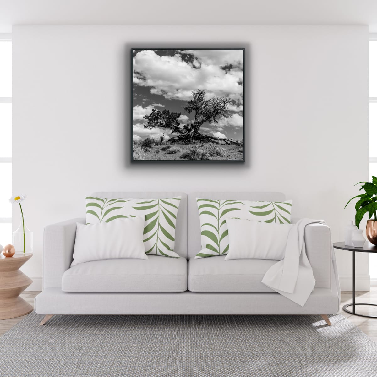 Framed black and white photograph of a large tree with a rugged trunk against a cloudy sky on a white wall in a retro styled white living room with green accents.