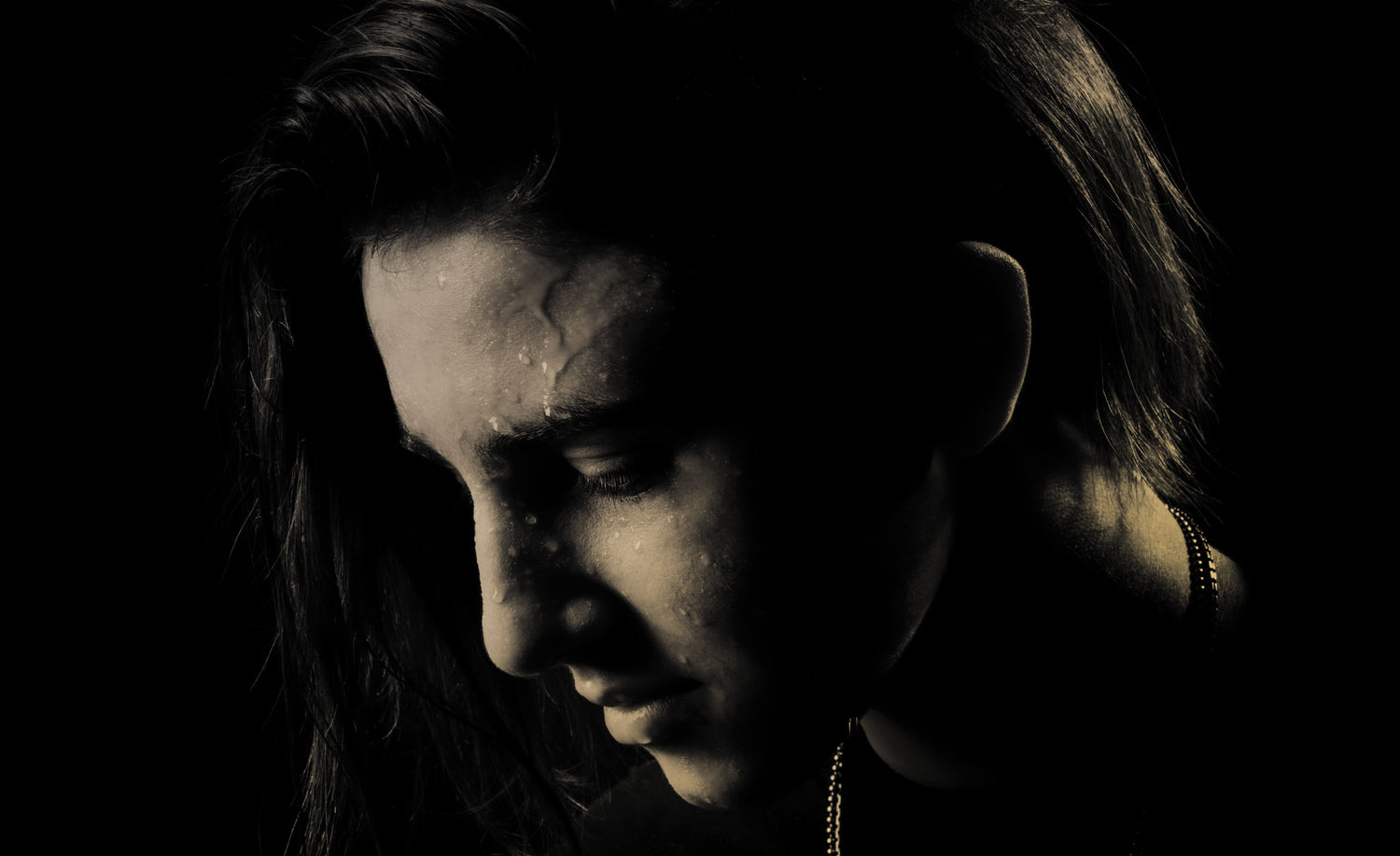 Black and white portrait of musician Dominique Ilie in Los Angeles  studio with black backdrop looking down and to the side