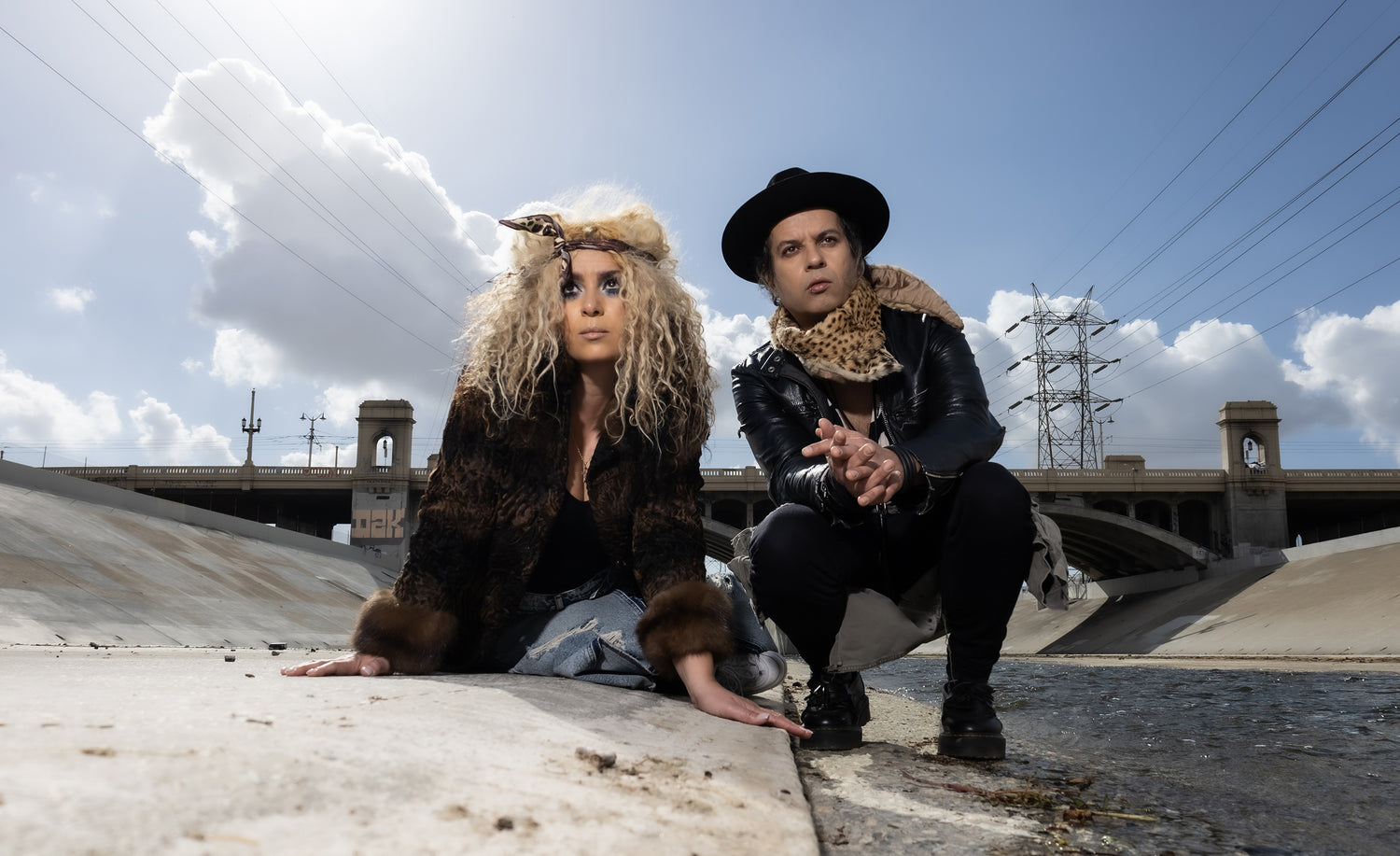 The Manic Boys And Girls Club kneeling down beside river with bridge behind