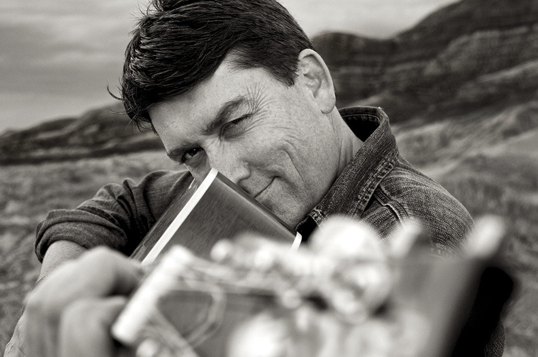 Black and white Musician portrait Blake Reid closeup pointing neck of guitar at camera