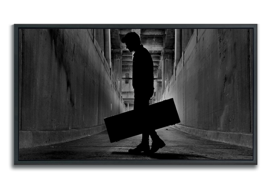 Black and white fine art photographic metal print framed silhouetted man holding guitar case in tunnel under bridge