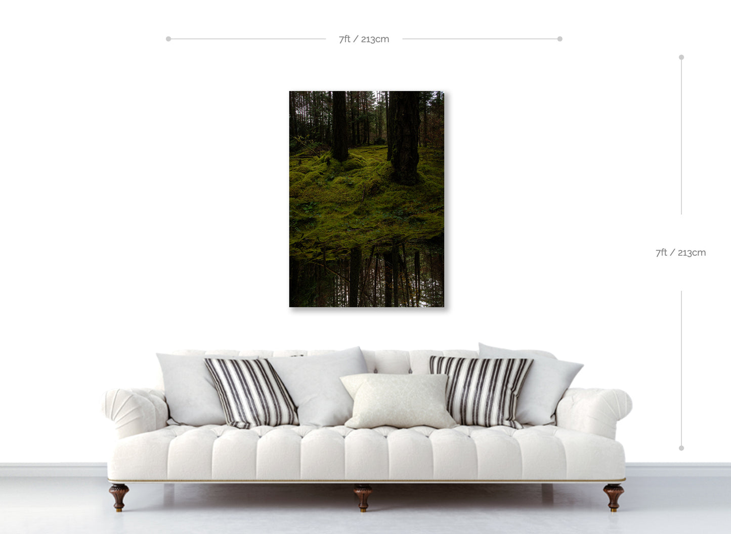 White sofa with decorative pillows in a room with a forest painting on the wall.