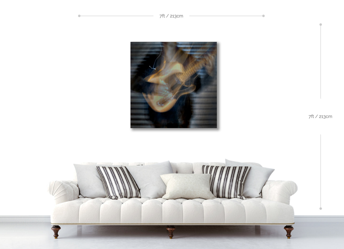 White sofa with striped cushions in a room with a guitar painting on the wall.