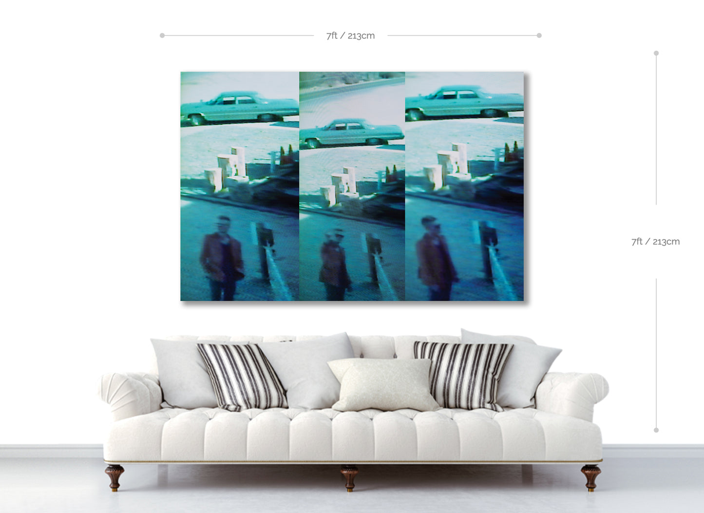 White sofa with decorative pillows in front of a wall art piece showing a collage of a man and a car.
