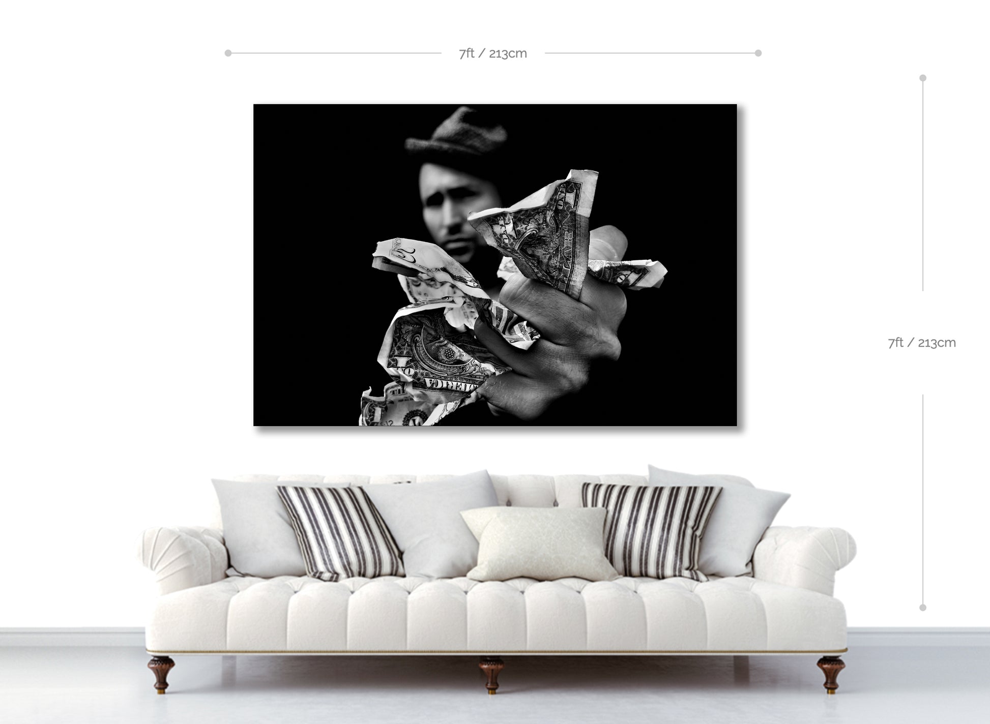 Framed black and white artwork of a person holding money over a white sofa.