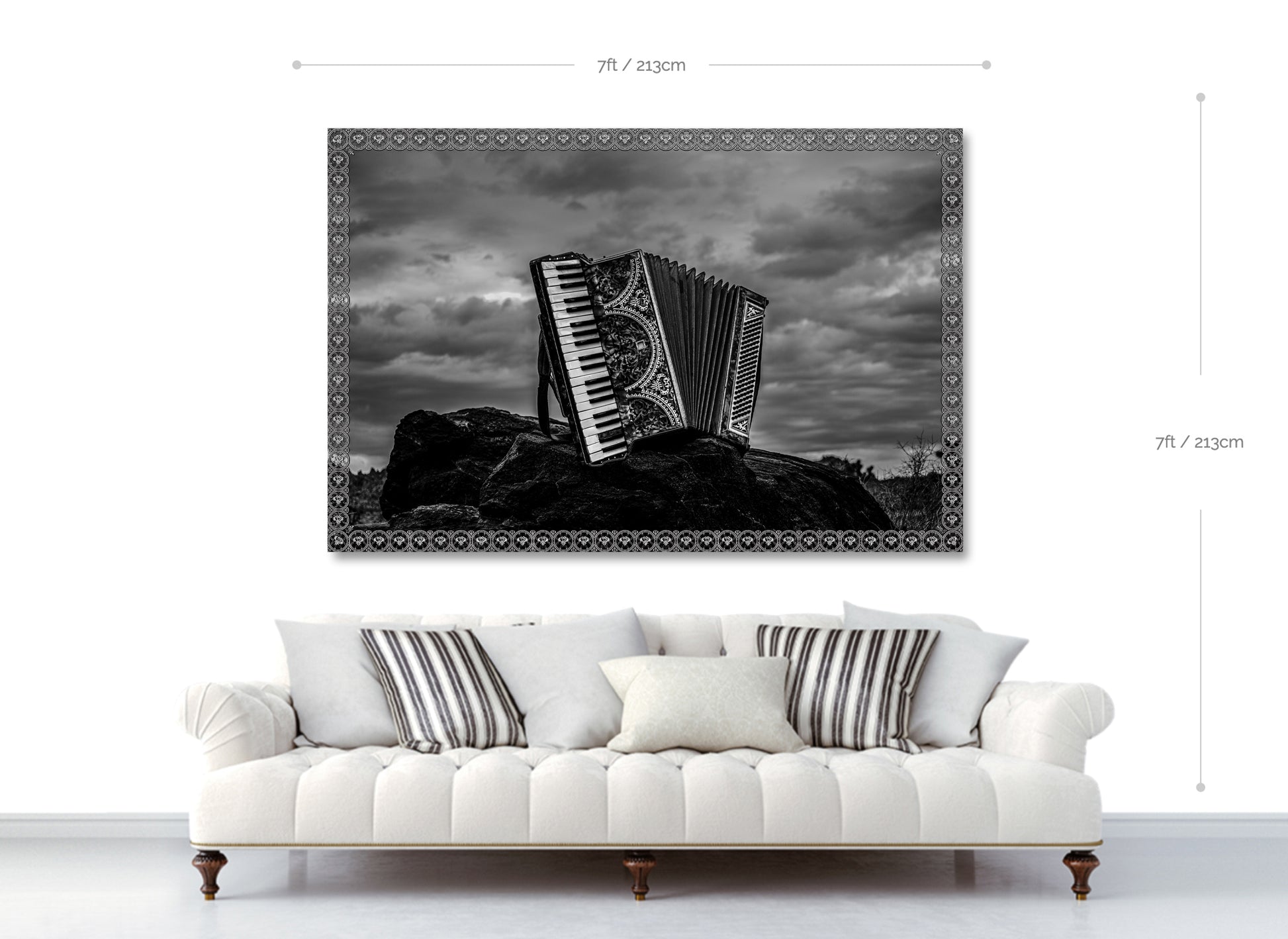 Framed black and white artwork of an accordion on a white wall above a white sofa.
