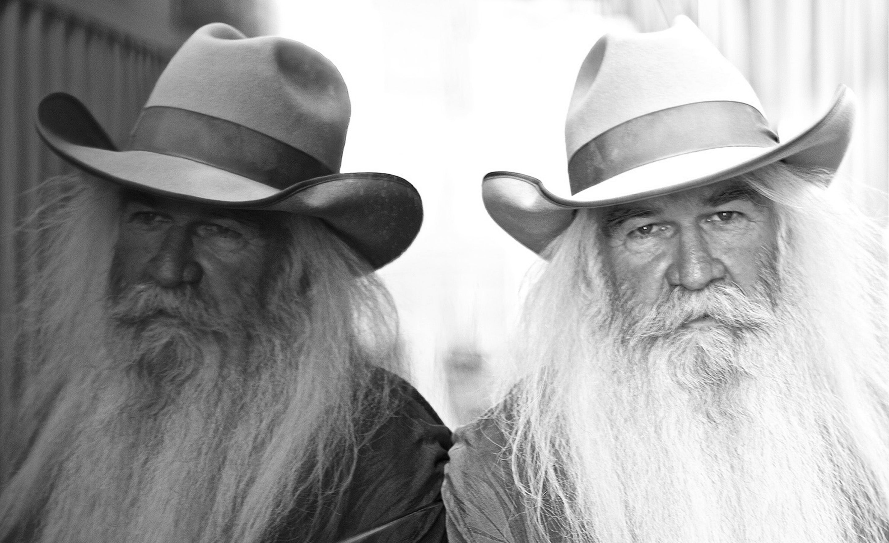 Fine art portrait William Lee Golden The Oakridge Boys wearing cowboy hat leaning against wall with his reflection mirrored beside him in black and white